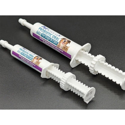 Two white syringe-style tubes of Mewbooster Probiotic Oral Gel for Dogs & Cats, displayed diagonally on a dark gray textured background.