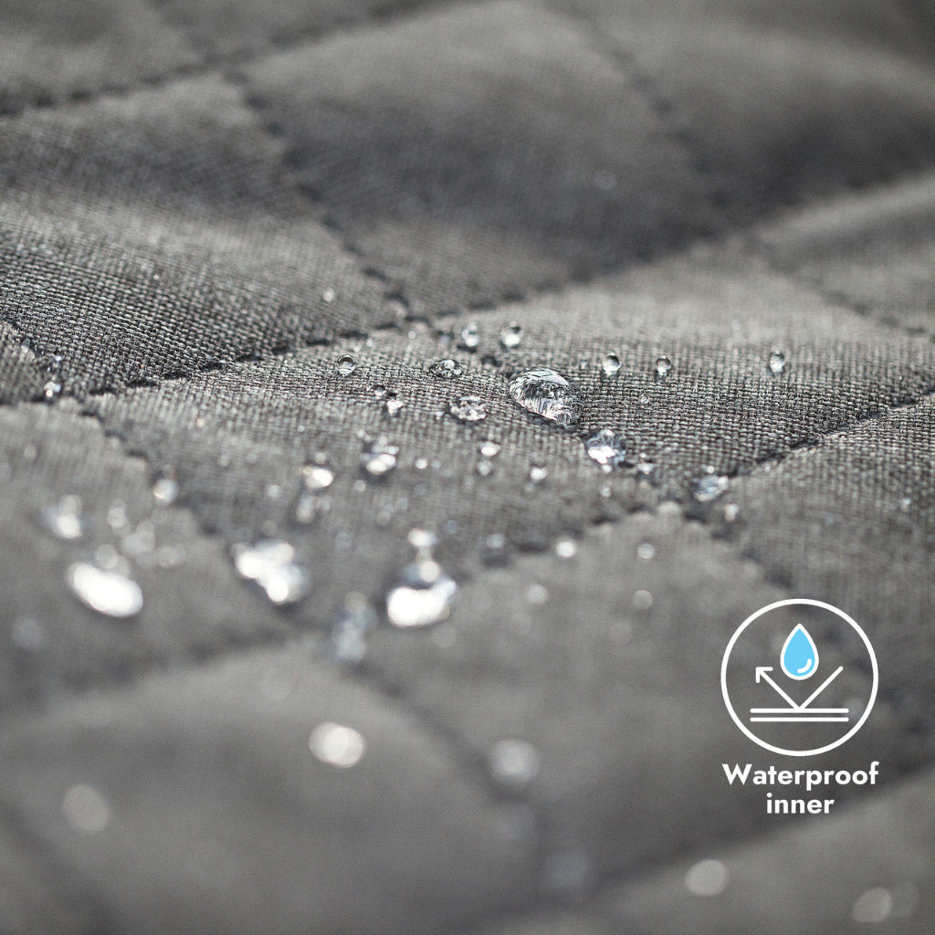 Close-up of gray quilted fabric with water droplets and a waterproof inner label.