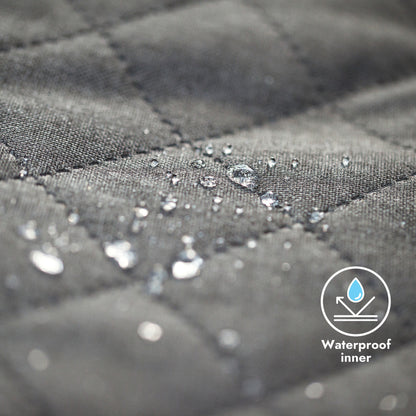 Close-up of gray quilted fabric with water droplets and a waterproof inner label.