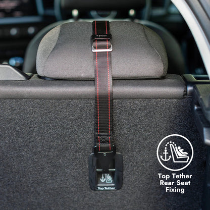 A black car rear seat top tether strap with red stitching and a silver buckle, shown attached to the headrest of a car seat. A circular graphic overlay on the bottom right reads 'Top Tether Rear Seat Fixing' with an icon.