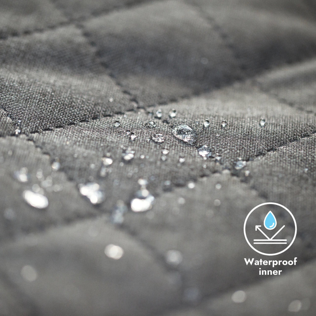 Close-up of gray quilted fabric with water droplets and a waterproof inner label.