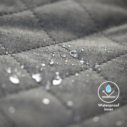 Close-up of gray quilted fabric with water droplets and a waterproof inner label.