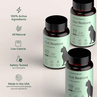 Three bottles of Animal Biome Gut Restore cat supplement capsules arranged on a light beige background with marketing text on the left. The bottles are dark amber with black caps and labels in pale mint green with black text and a black cat silhouette.